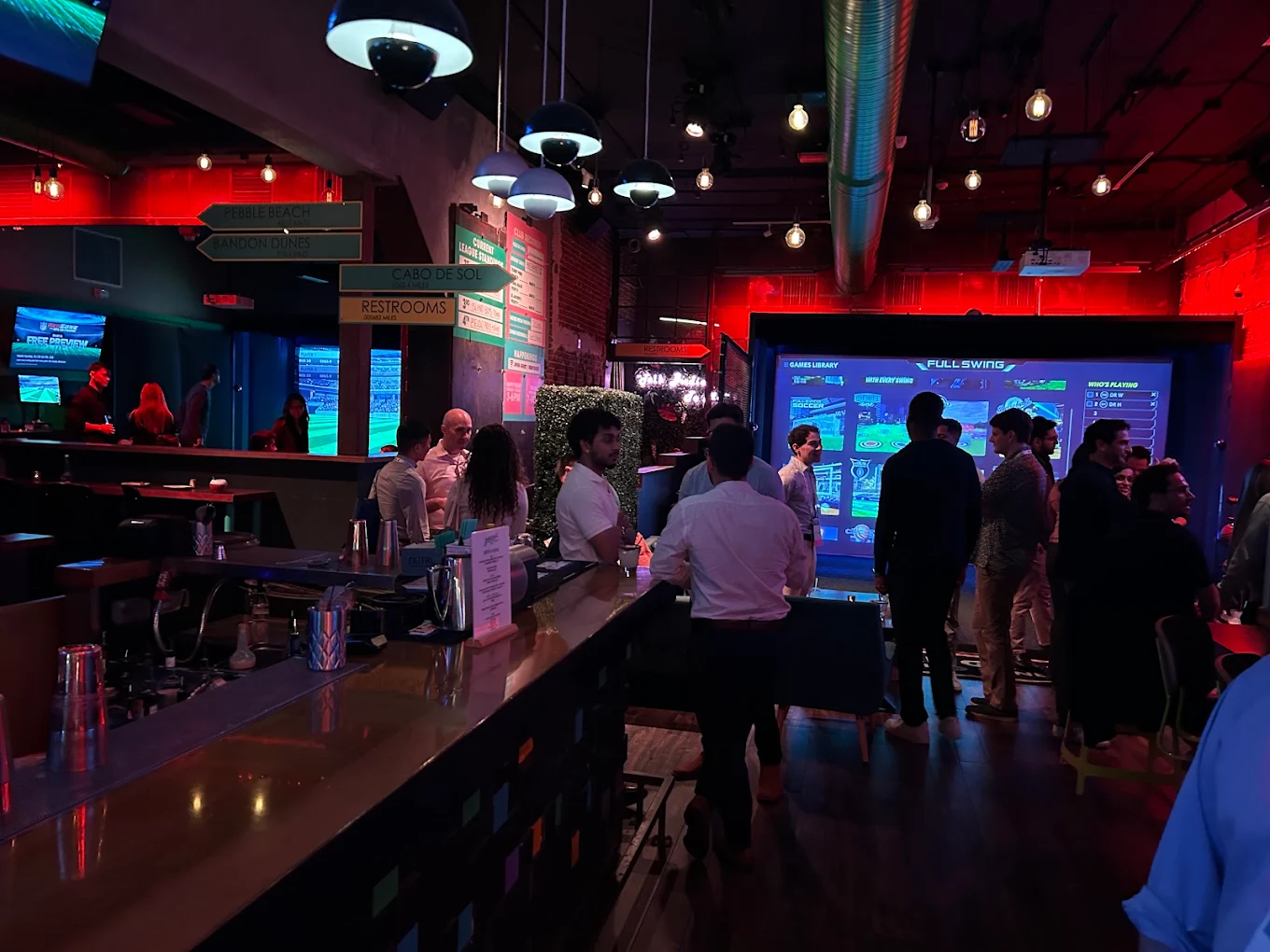 Guests enjoying a private event at Swing Social with the Full Swing simulator lit up